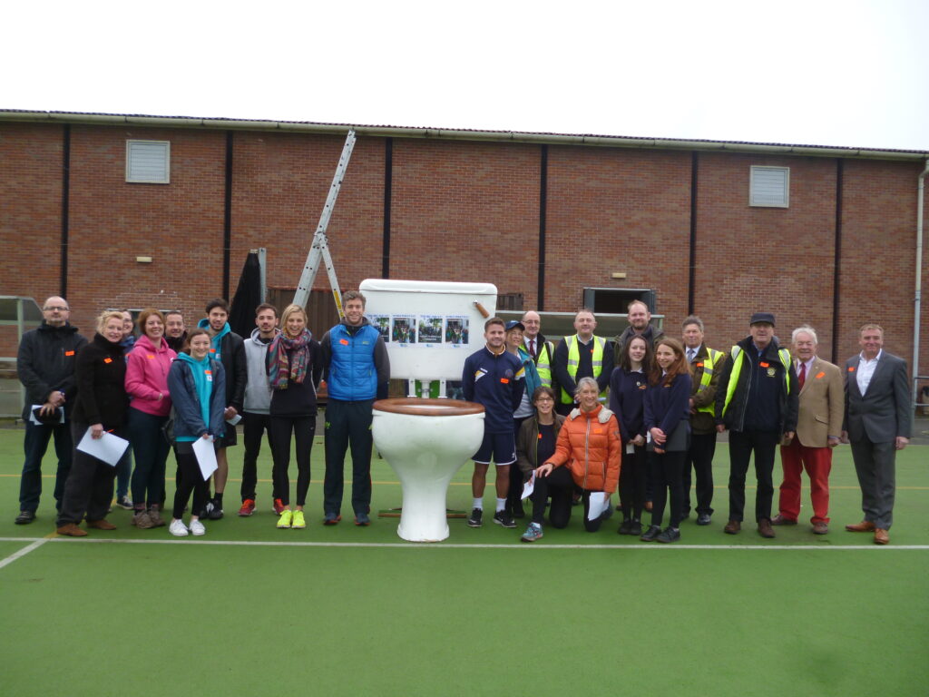 Group of people around a toilet - fundraising