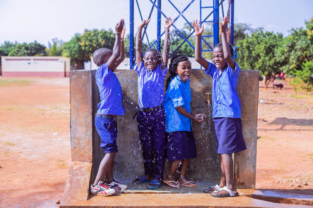 School children splashing in water with smiles