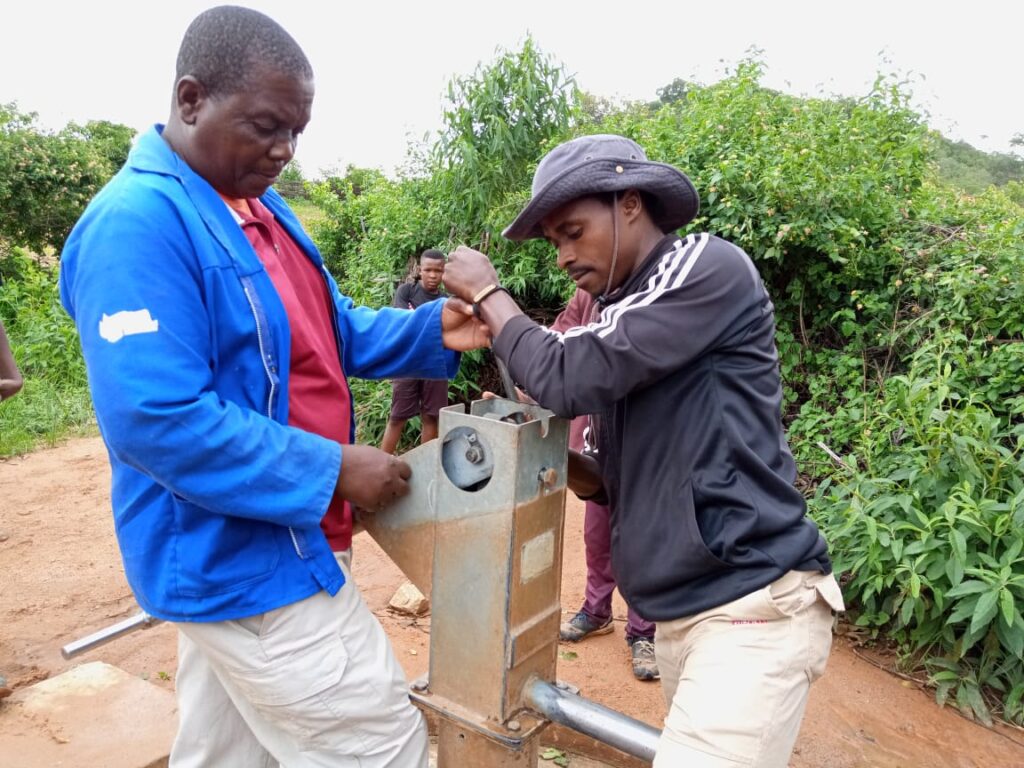 Two men working and fixing broken water pumps